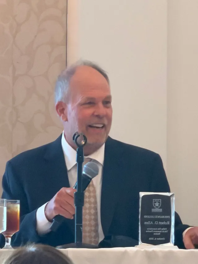 Bob Allen speaking into a microphone beside his Insurance Legend award